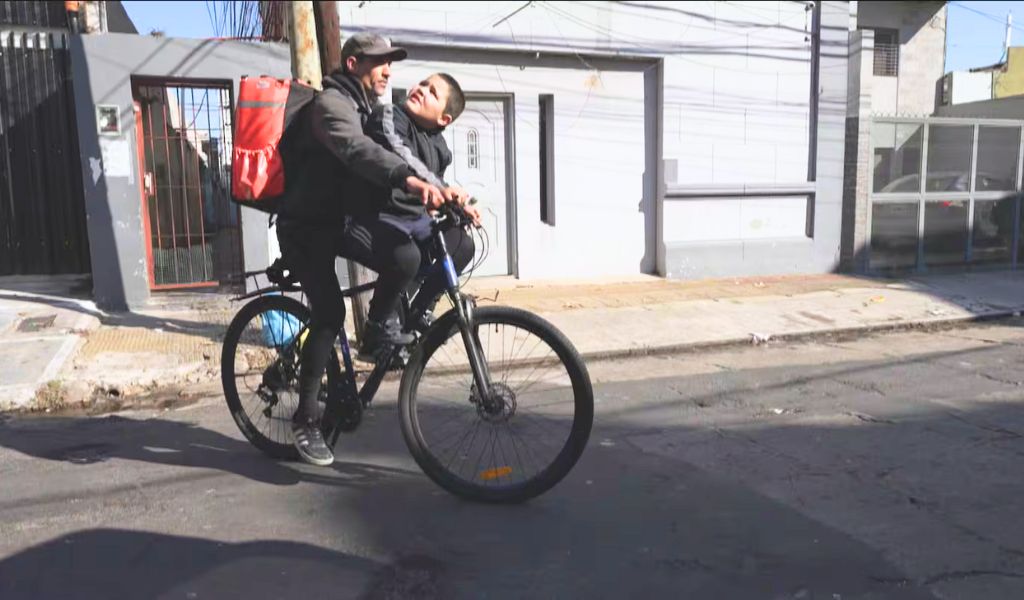“La elección diaria del amor”: vende prepizzas en bicicleta junto a su hijo con autismo para poder cuidarlo cada día